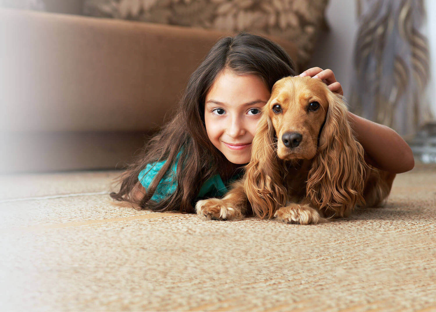 young girl and dog laying on carpet